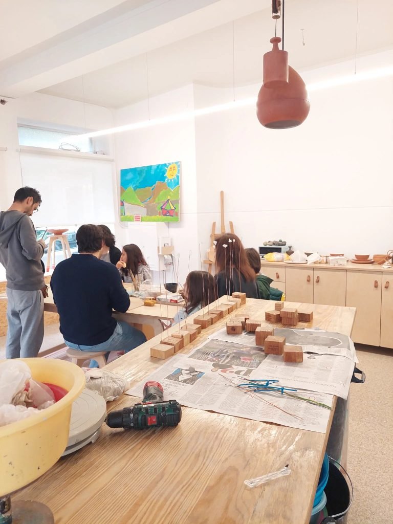 Parent and child hand-building ceramic bowl together during family pottery workshop Porto