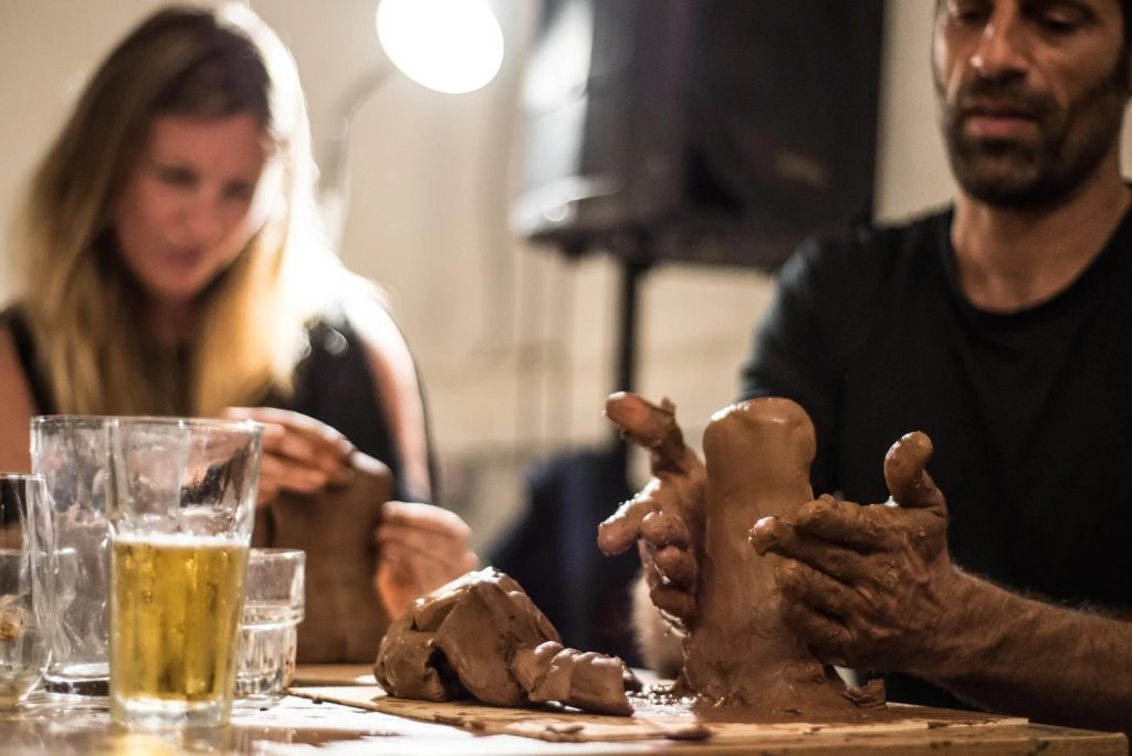 Couple sculpting clay from live model during romantic evening art workshop with wine Lisbon